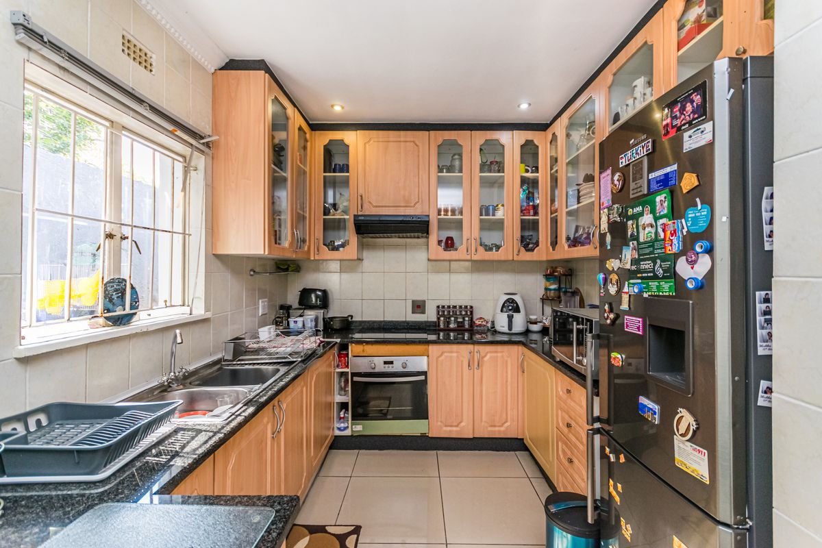 A functional kitchen featuring light wood cabinetry, granite countertops, a double basin sink, and built-in oven with extractor fan.