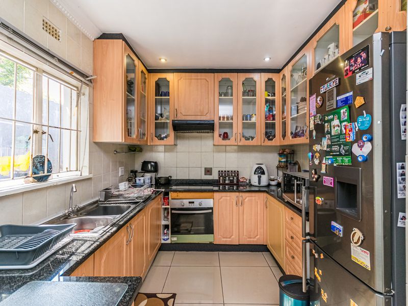 A functional kitchen featuring light wood cabinetry, granite countertops, a double basin sink, and built-in oven with extractor fan.