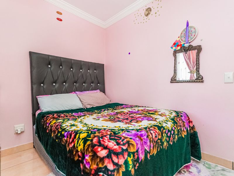 A bedroom featuring tiled flooring and decorative crown molding, currently finished with pink wall paint.