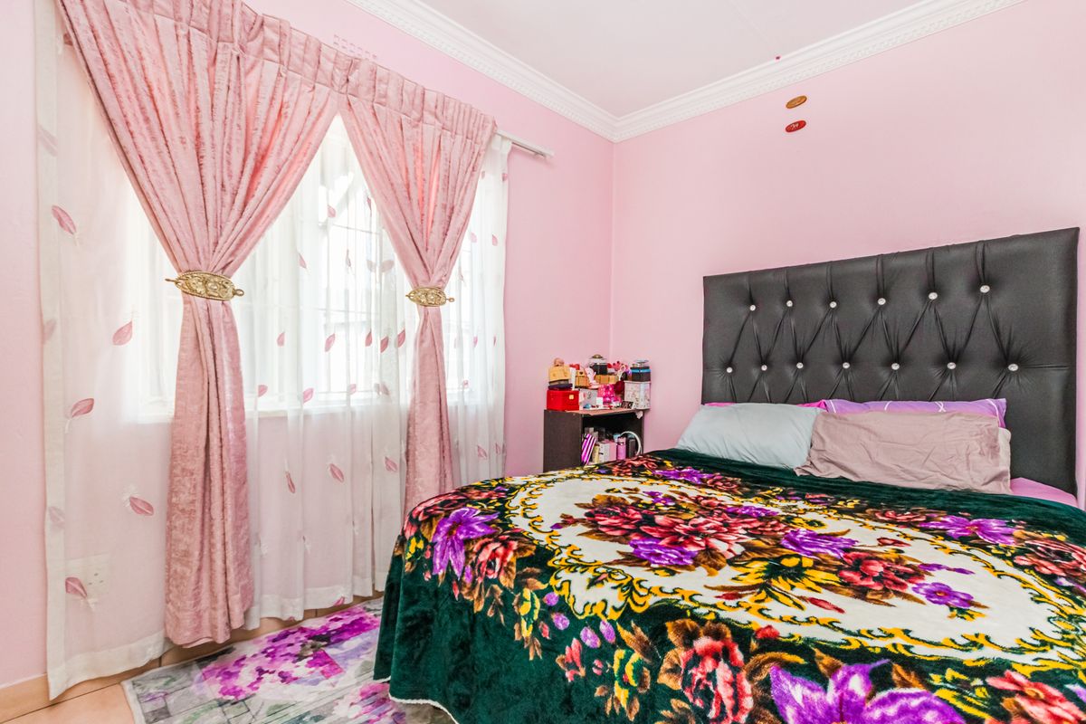 A bedroom featuring tiled flooring and decorative crown molding, finished with pink wall paint.