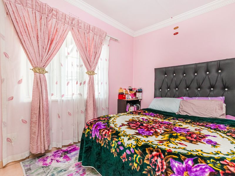 A bedroom featuring tiled flooring and decorative crown molding, finished with pink wall paint.