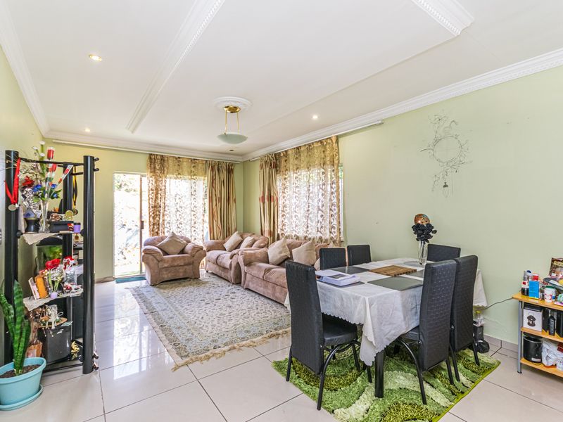 Open plan living and dining area featuring tiled flooring, decorative ceiling cornices, and access to the exterior via a sliding glass door.