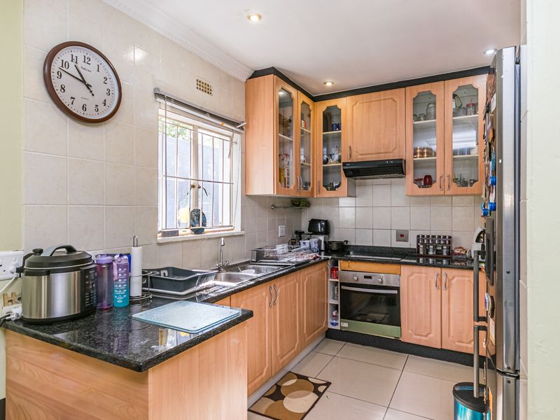A functional kitchen featuring light wood cabinetry, granite countertops, a built-in oven, and a tiled backsplash with a window overlooking the exterior.