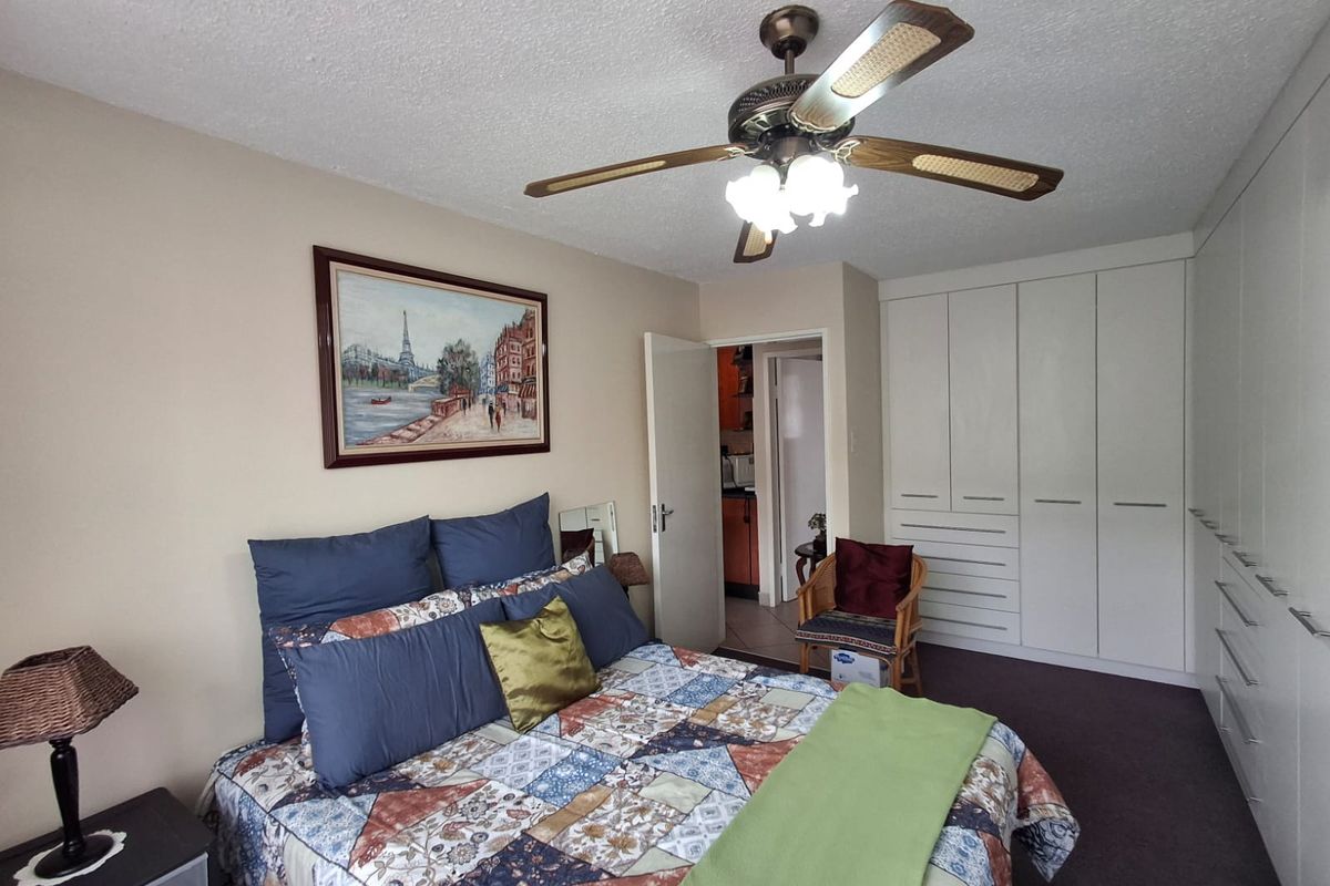 A well-maintained bedroom featuring extensive built-in cupboards and a central ceiling fan, offering functional storage and comfortable living space.