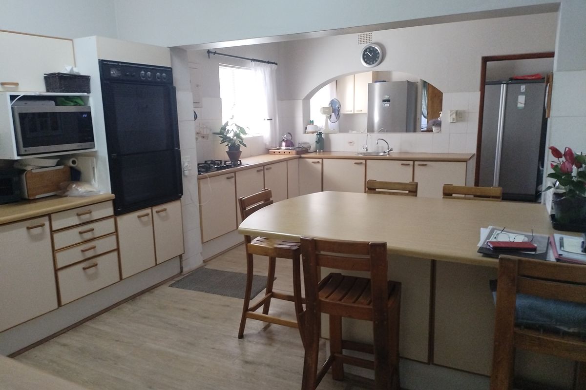 Spacious kitchen featuring built-in oven, integrated cabinetry, and a central breakfast bar, offering a functional layout with ample storage and preparation space.