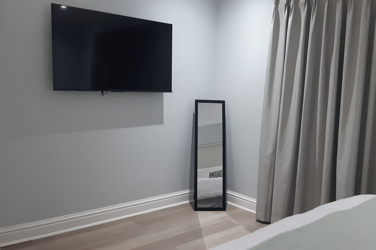 A well-maintained bedroom featuring neutral wall tones, modern laminate flooring, and classic skirting boards.