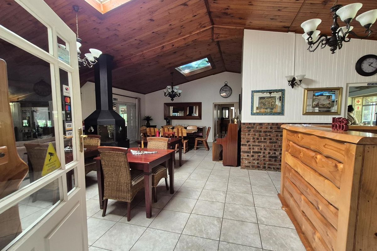 Spacious living area featuring a high exposed timber ceiling with skylights, tiled flooring, and a central freestanding fireplace, creating a warm, rustic atmosphere.