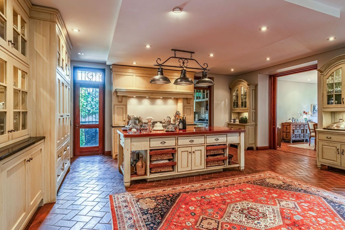 Spacious farmhouse-style kitchen featuring custom cabinetry, a central island with a countertop, terracotta floor tiles, and recessed lighting.