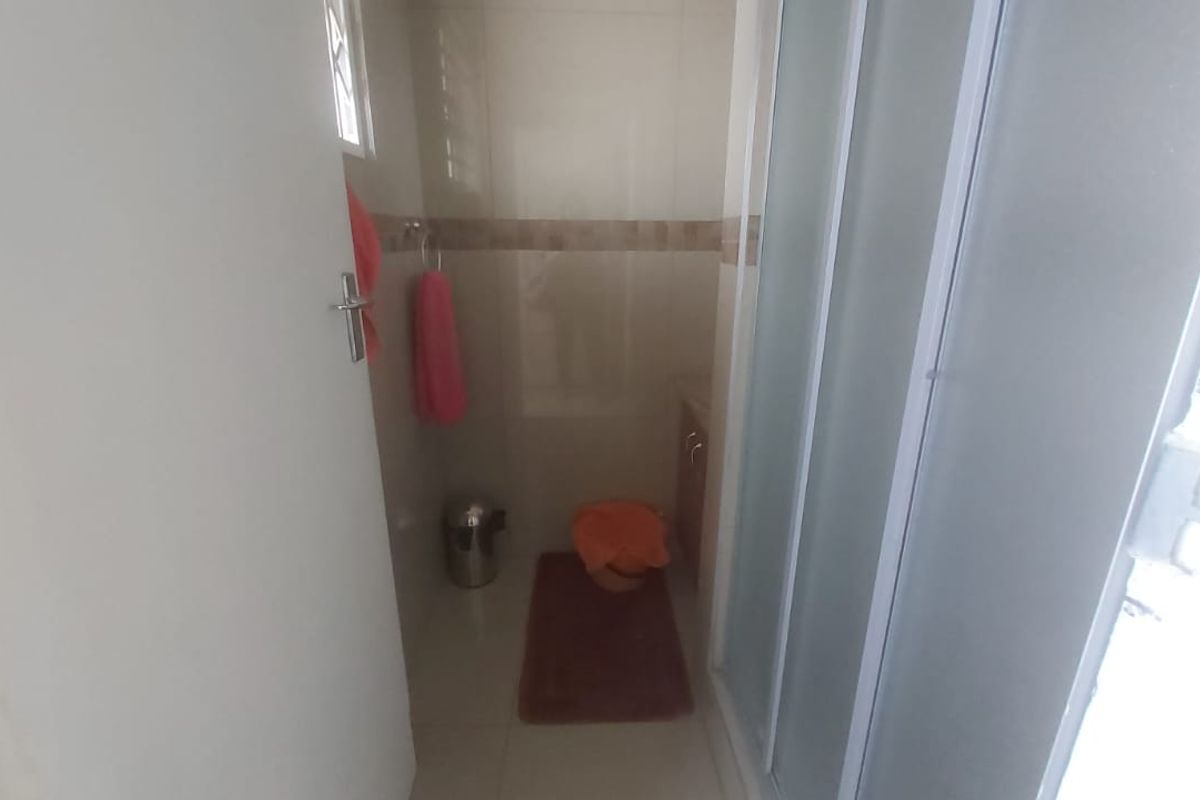 A compact bathroom featuring a shower enclosure, tiled finishes, and a built-in vanity cabinet.