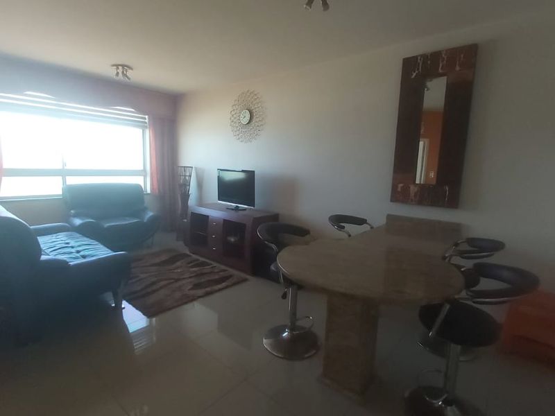 Open plan living and dining area featuring tiled flooring and large windows, providing a functional space for relaxation and meals.