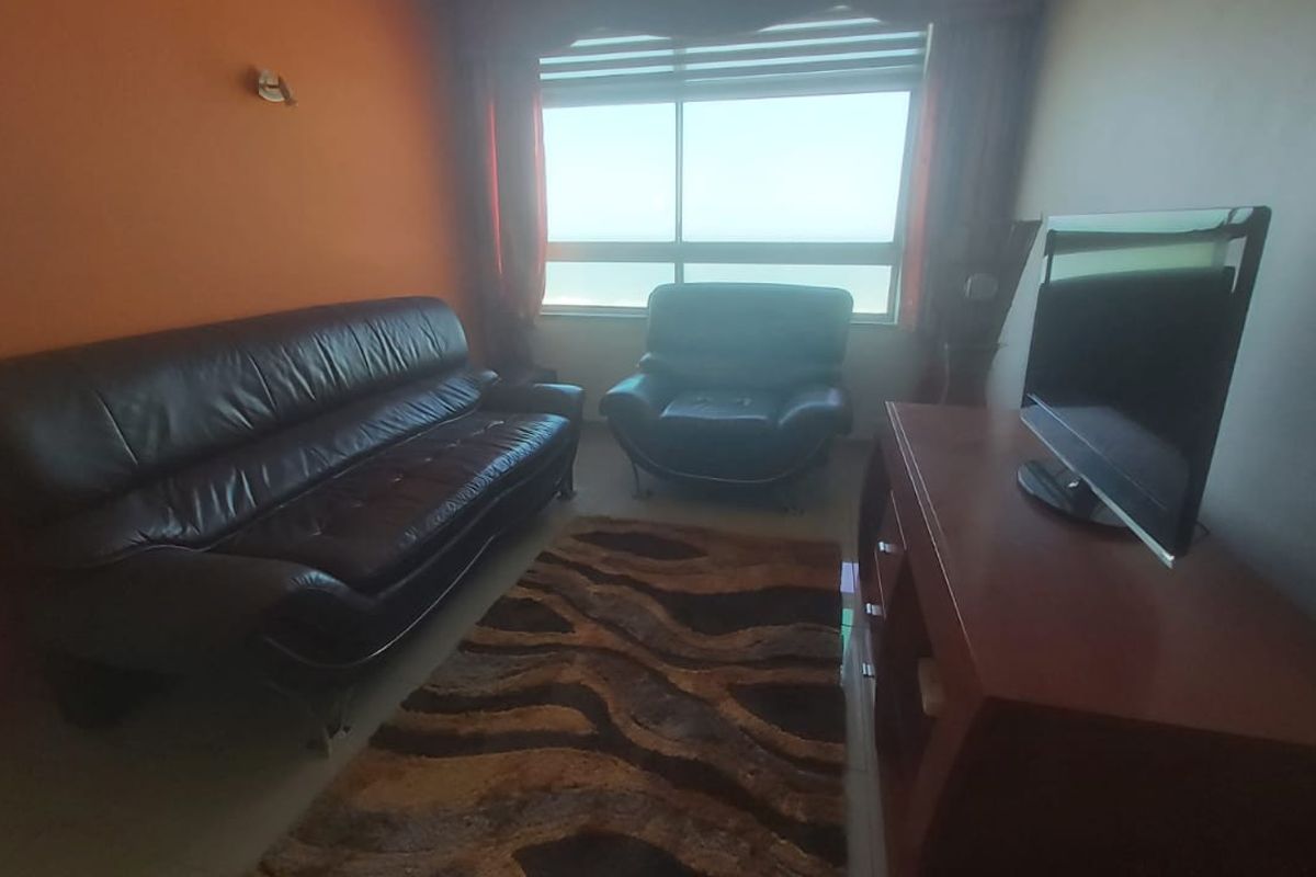 A living room featuring a large window with natural light and an accent wall.
