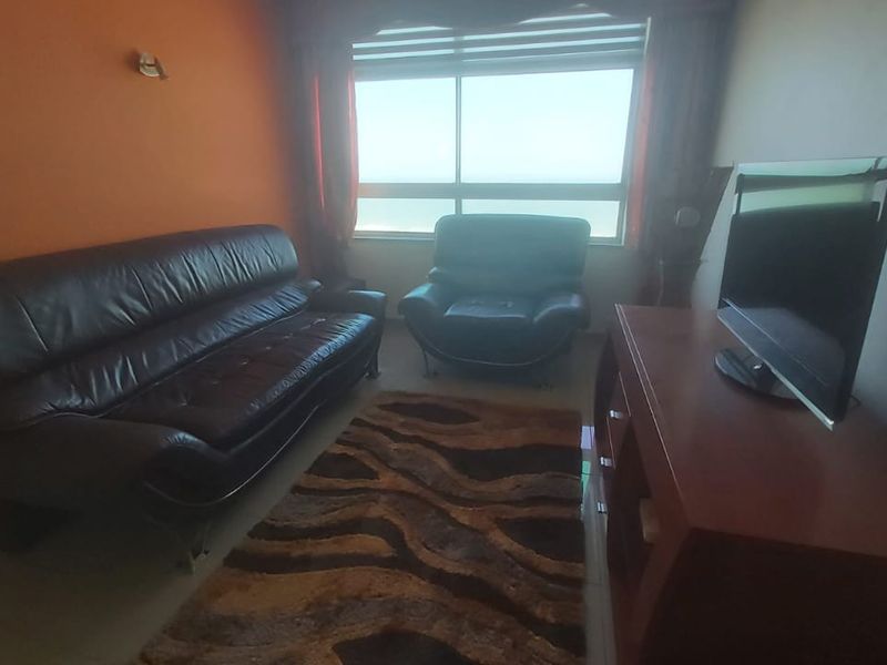 A living room featuring a large window with natural light and an accent wall.