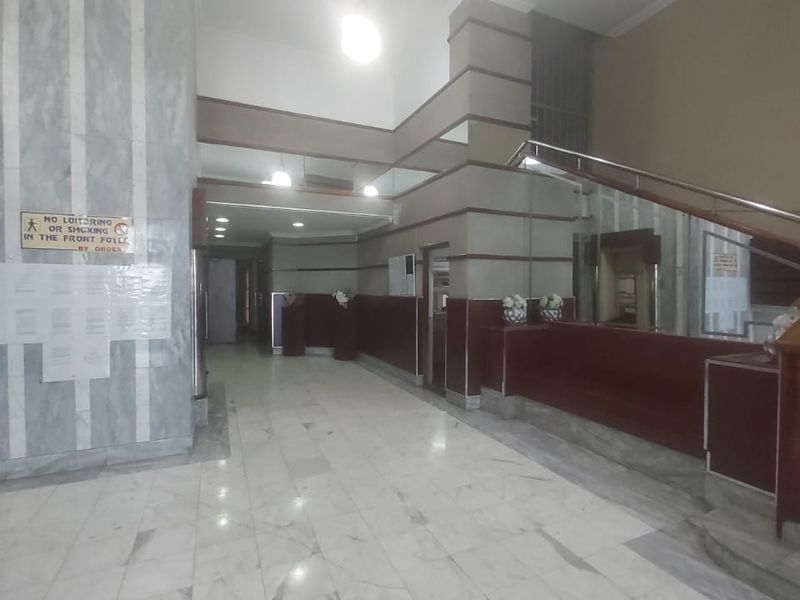 Spacious apartment building entrance foyer featuring marble flooring, a staircase with a wooden handrail, and integrated mailboxes.