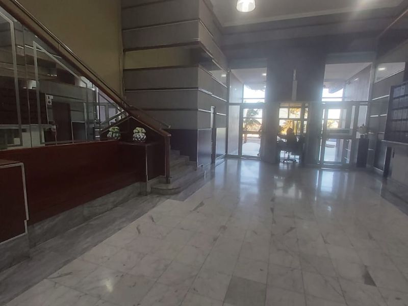 Spacious apartment building entrance lobby featuring marble flooring, a staircase with a glass balustrade, and integrated mailboxes.