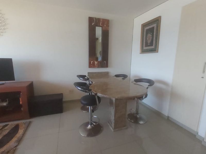 An open-plan living and dining area featuring tiled flooring and a built-in cupboard, offering a functional layout for daily living.