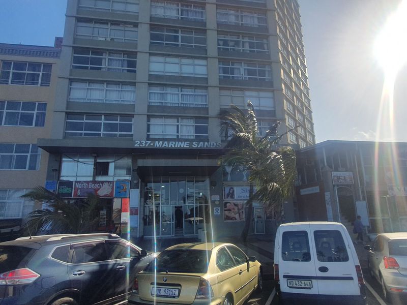 Front elevation of the Marine Sands apartment building, featuring a glass entrance and street-level commercial frontage.