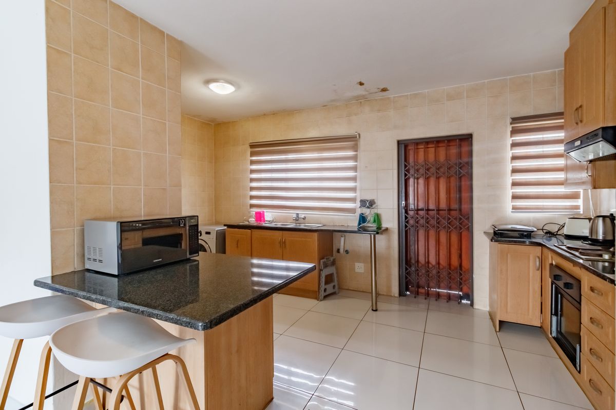 A functional kitchen featuring granite countertops, built-in cabinetry, and tiled finishes, requiring minor ceiling repairs.