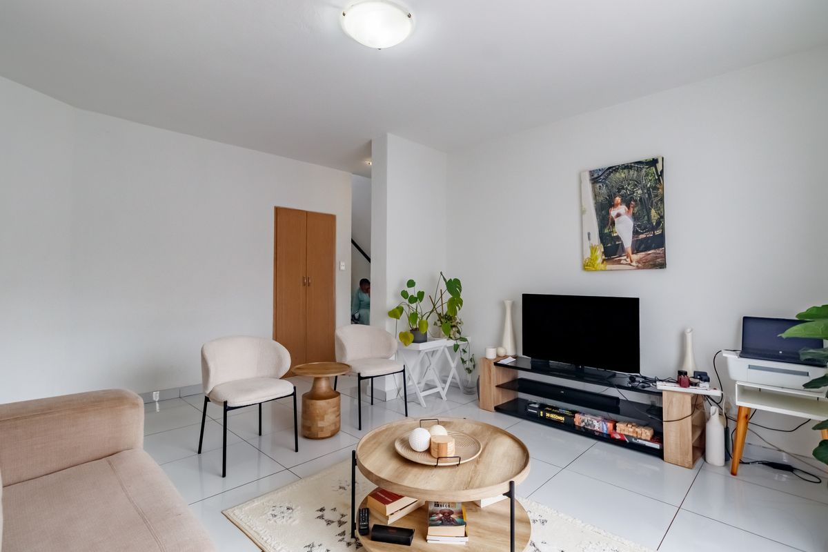 A bright living room featuring polished white floor tiles and a built-in storage cupboard, offering a clean and neutral space for relaxation.