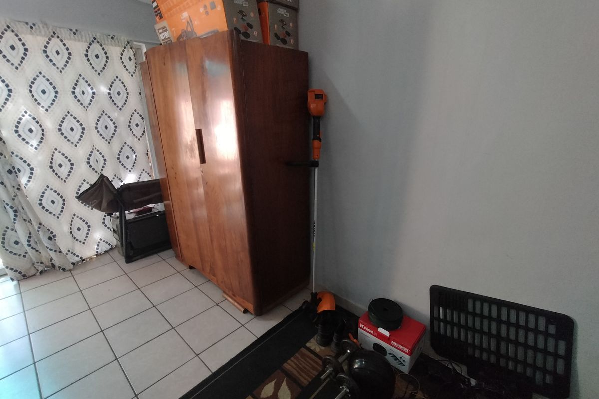 A living area featuring tiled flooring and neutral wall finishes, currently utilized for storage.