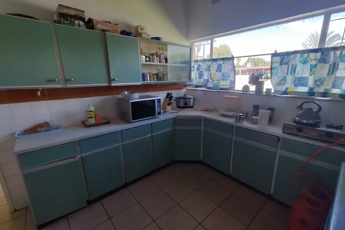 A dated kitchen featuring original green cabinetry, tiled splashbacks, and tiled flooring, offering significant potential for a modern renovation.