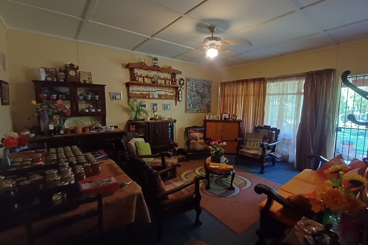 A spacious living room featuring a ceiling fan, large windows with curtains, and direct access to the outdoor area.