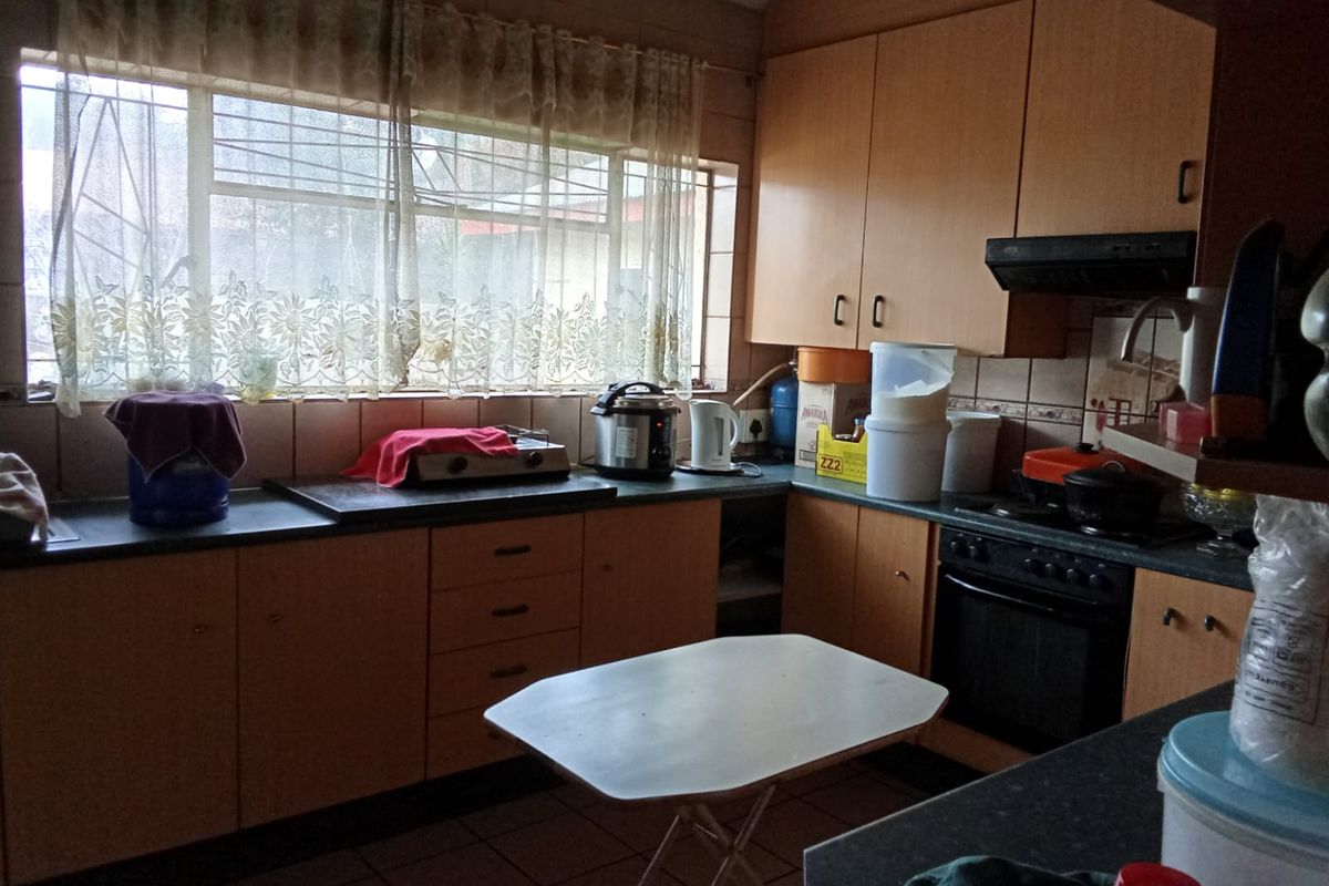 A functional kitchen featuring laminate cabinetry, built-in oven, extractor fan, and tiled splashbacks, offering a dated aesthetic ready for modernization.