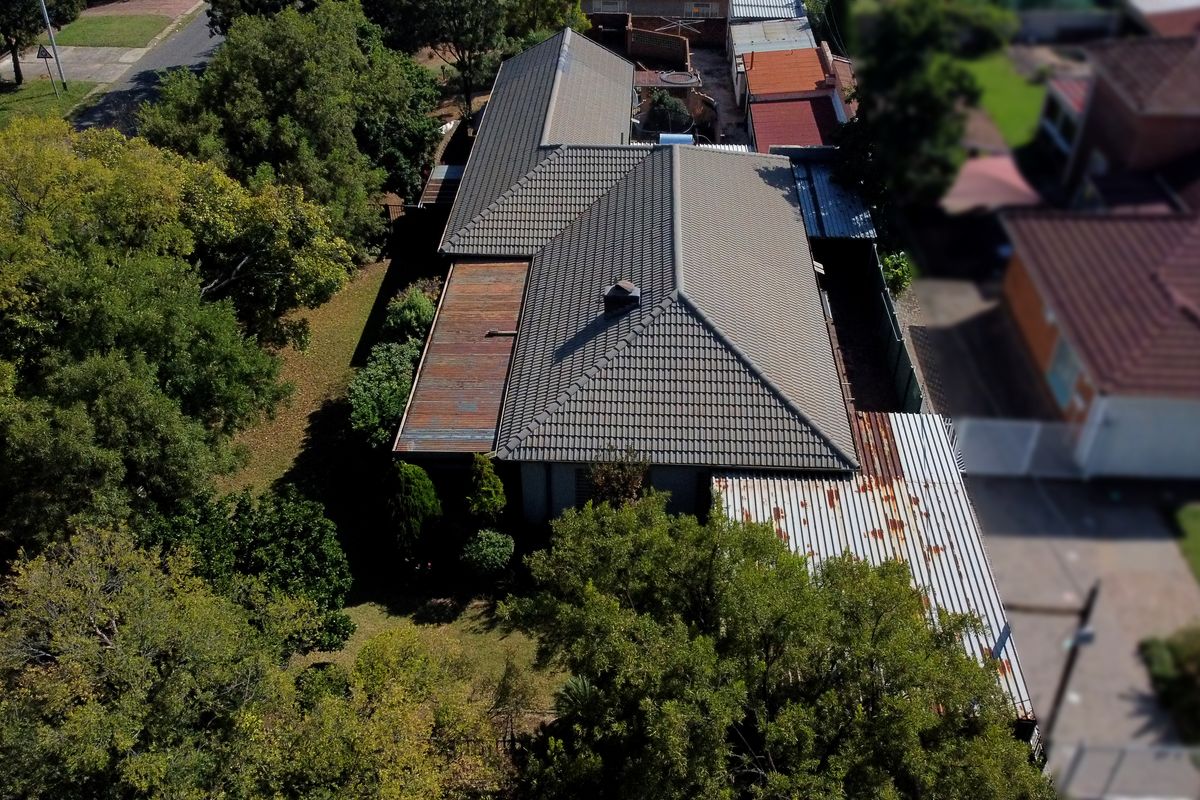 Aerial view of the property showing the main tiled roof structure and secondary corrugated metal roofing sections with visible signs of corrosion.