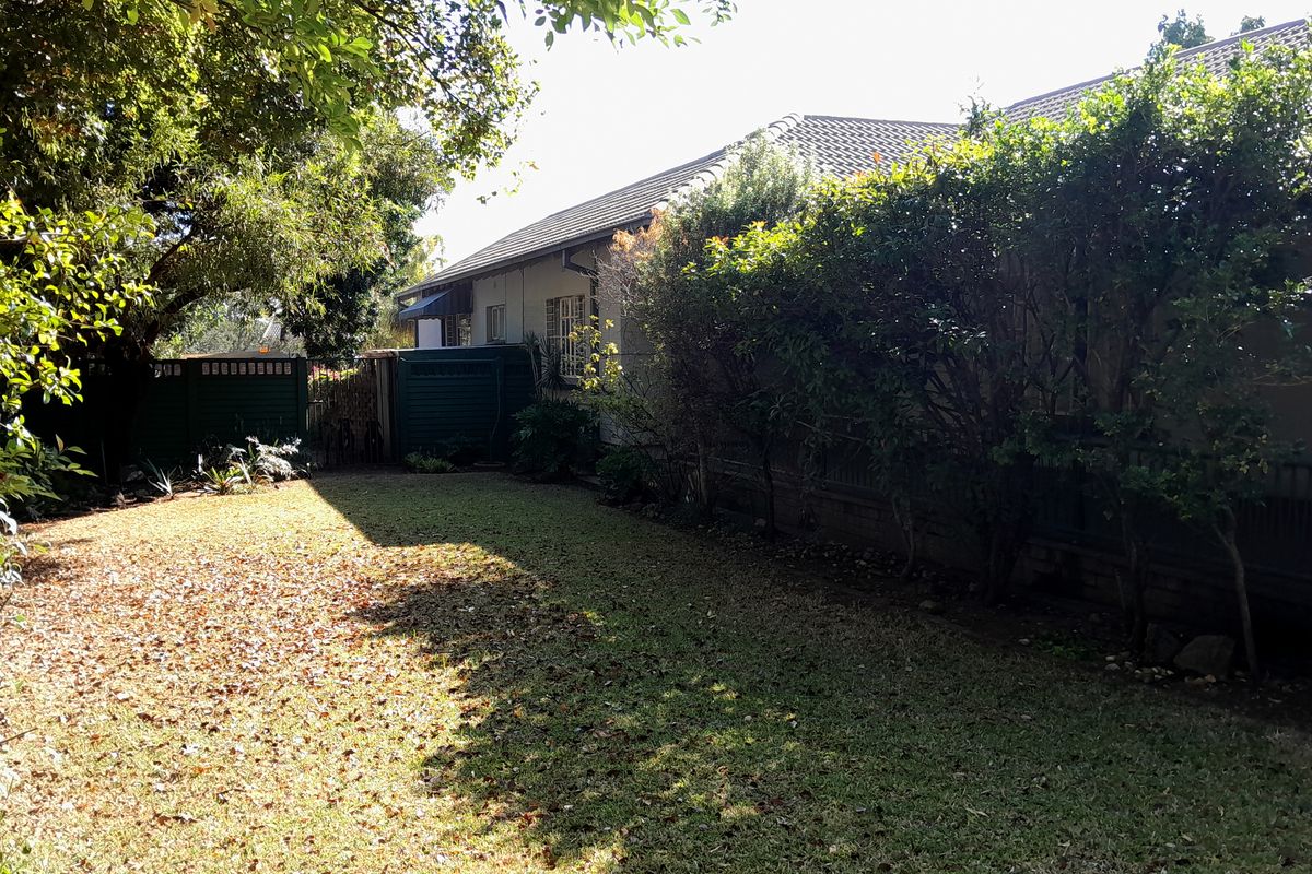 A view of the rear garden and side elevation of the house, featuring a tiled roof and established landscaping.
