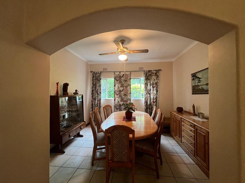 A traditional dining room featuring tiled flooring, a ceiling fan, and an arched entryway, providing a functional space for family meals.