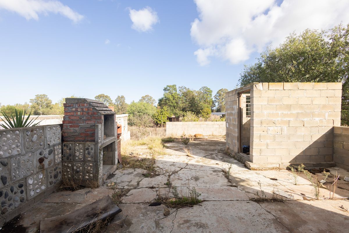 Outdoor area featuring a concrete patio, a built-in brick braai, and an unfinished masonry structure on a residential vacant land plot.