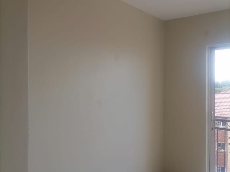 An empty bedroom featuring tiled flooring, neutral walls, and a sliding glass door providing access to a balcony.