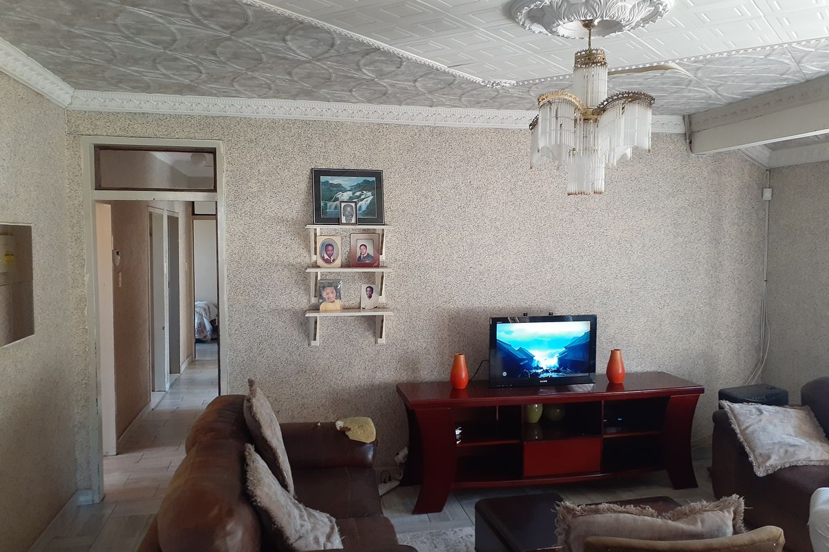 A living room featuring a decorative ceiling with a chandelier, textured wall finishes, and access to a hallway.