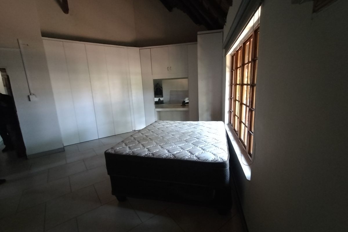 Spacious bedroom featuring vaulted ceilings, extensive built-in cabinetry, and large timber-framed windows allowing for natural light.