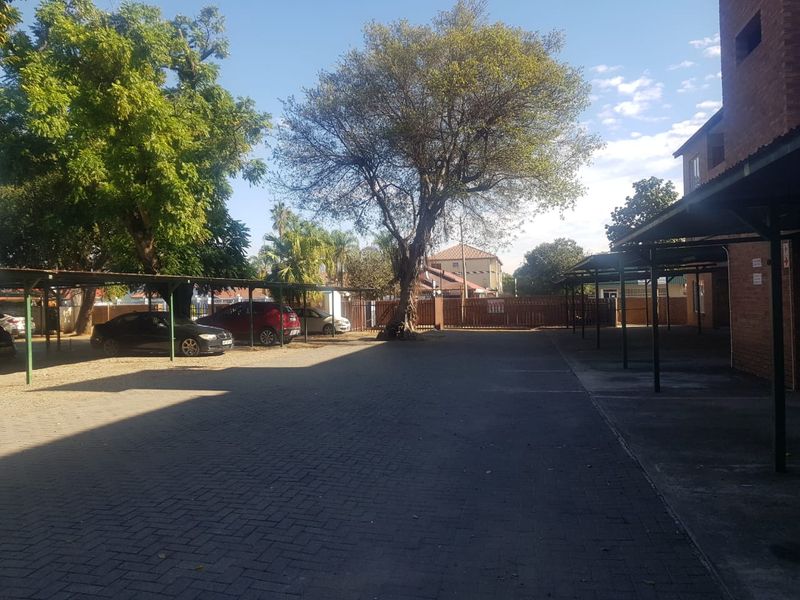 An outdoor parking area featuring covered carports and paved driveway space within the apartment complex grounds.