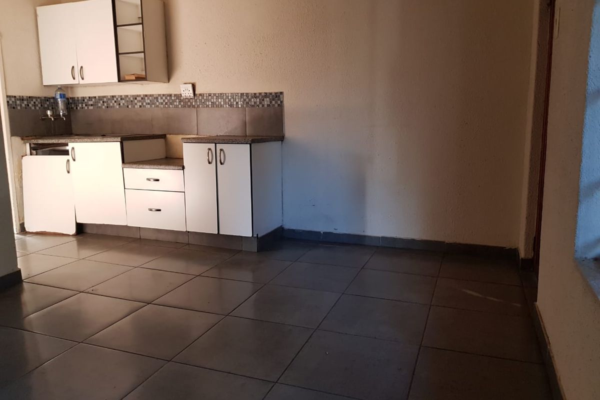 A compact kitchen area featuring tiled flooring, mosaic backsplash, and built-in cabinetry, currently requiring minor repairs and cosmetic updates.