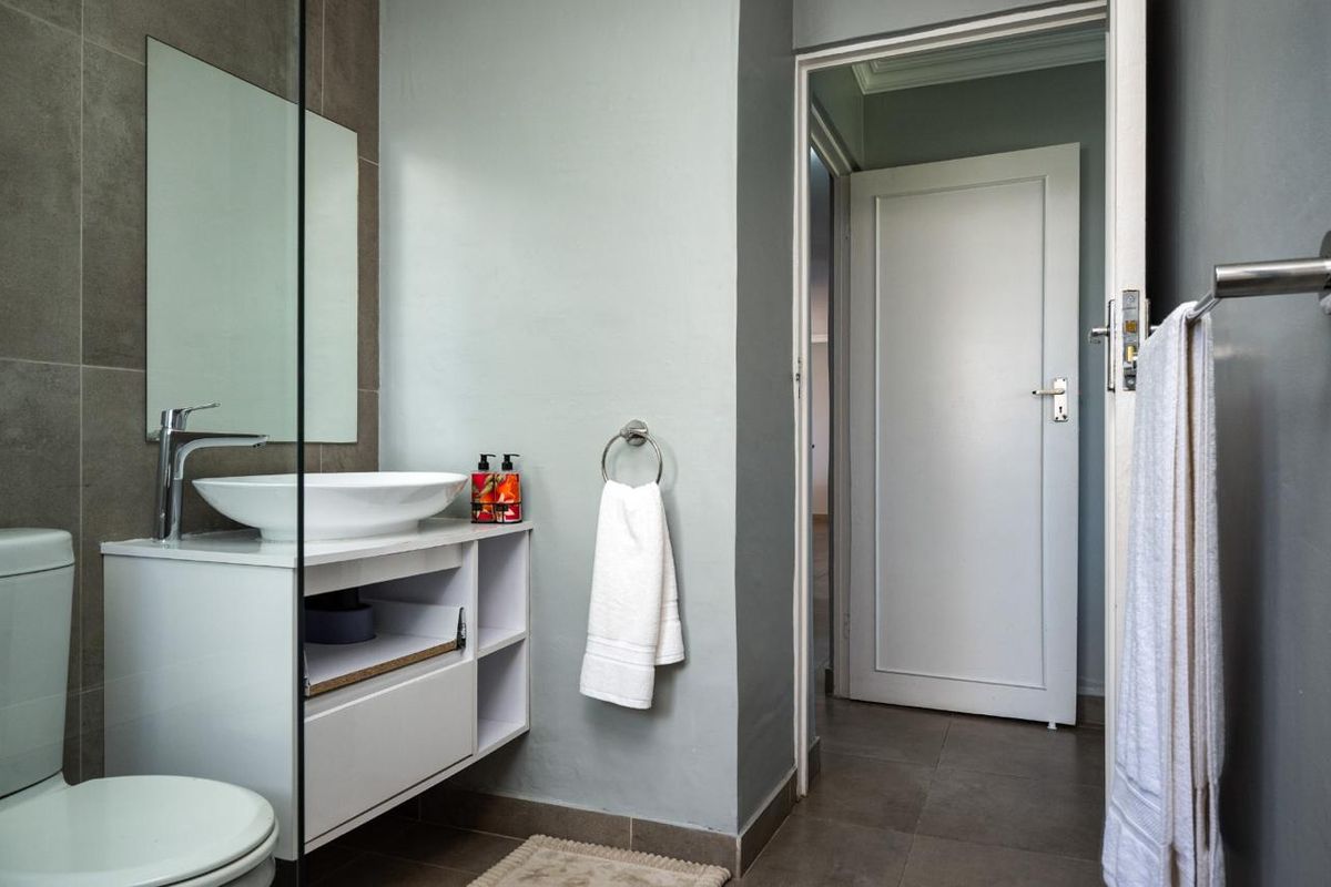 Modern bathroom featuring a vessel sink on a white vanity cabinet, tiled walls, and neutral grey tones.