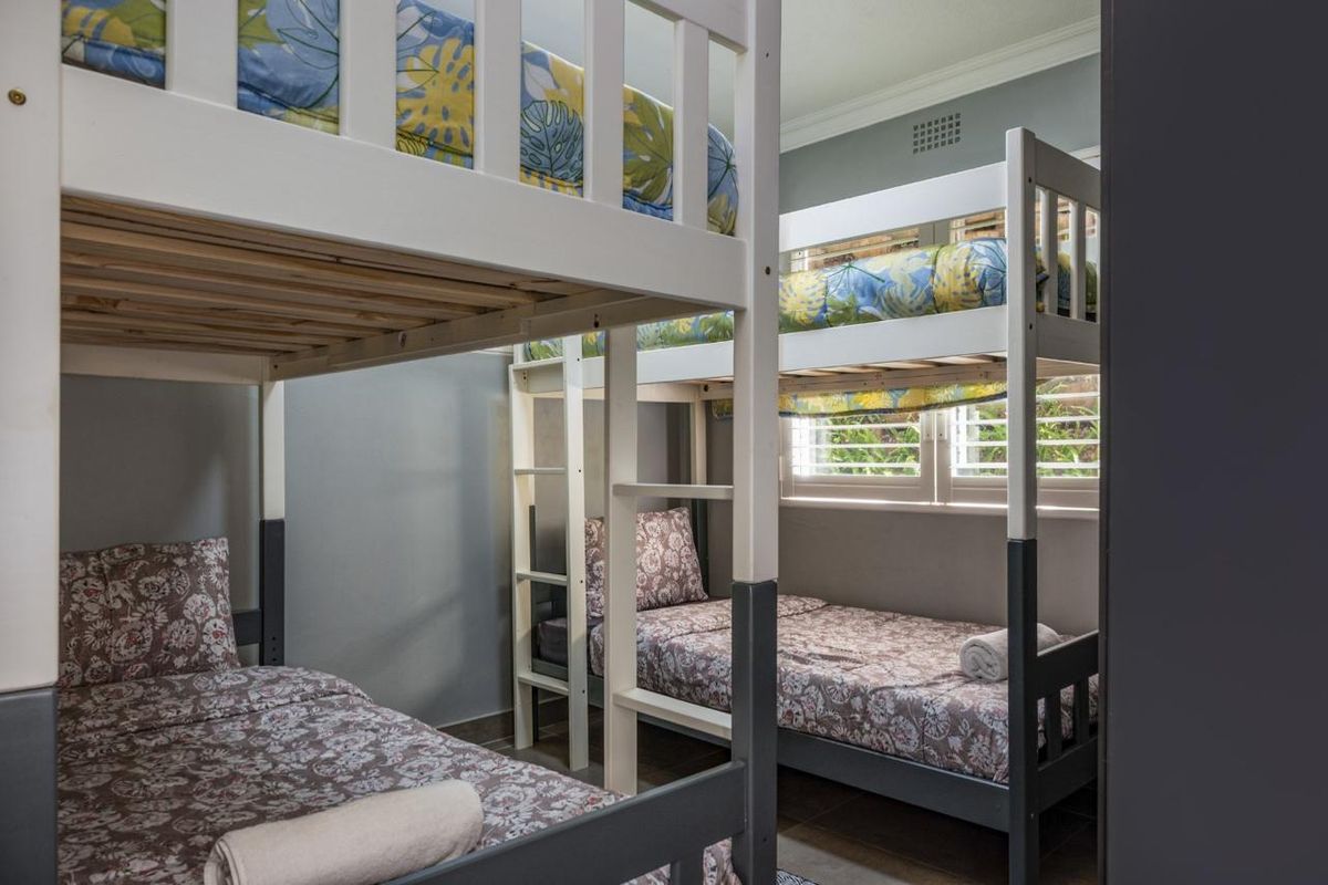 A functional bedroom featuring tiled flooring, crown molding, and plantation shutters, currently configured with bunk beds.