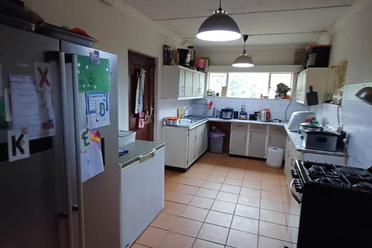 A functional kitchen featuring tiled flooring, built-in cabinetry, and a tiled backsplash, offering a practical layout with potential for modern updates.