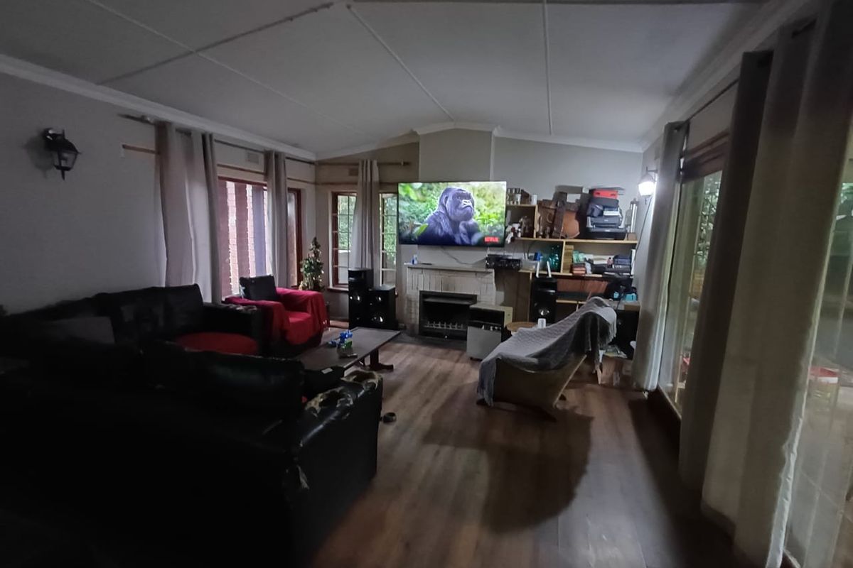 Spacious living room featuring a central fireplace, laminate flooring, and large sliding glass doors providing natural light and garden access.