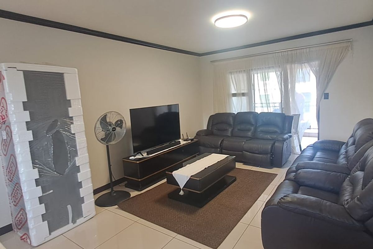 A living room featuring tiled flooring, crown molding, and a sliding glass door providing access to an outdoor area.