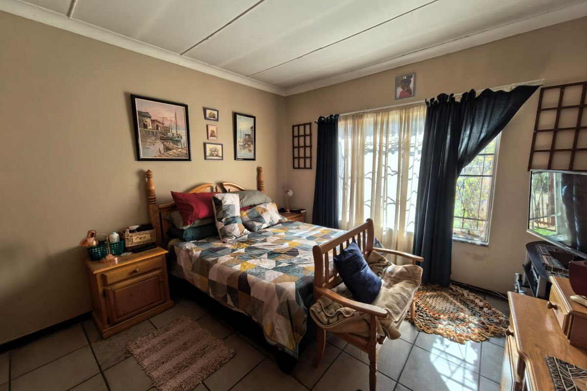 A bedroom featuring tiled flooring and a window with security bars, offering a functional space with potential for cosmetic updates.