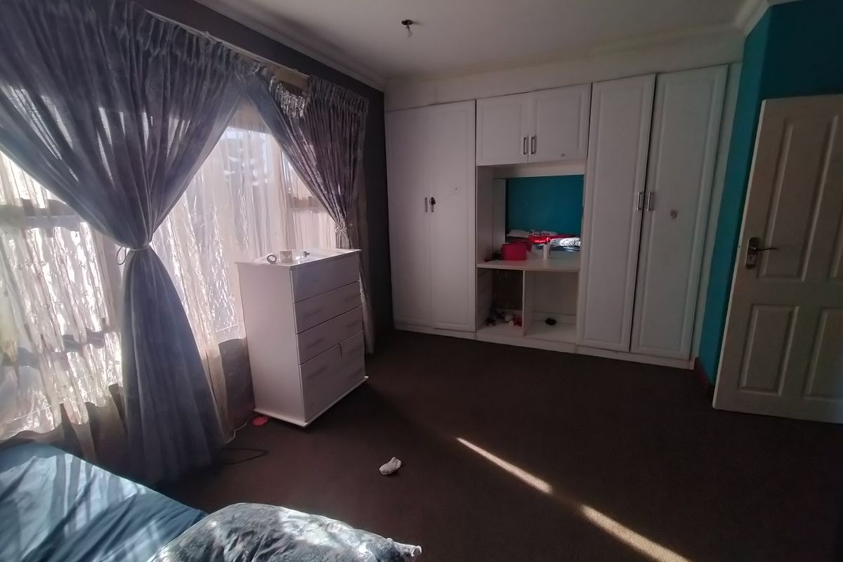 A bedroom featuring built-in cupboards, carpeted flooring, and coved ceiling details, offering a functional space with natural light.