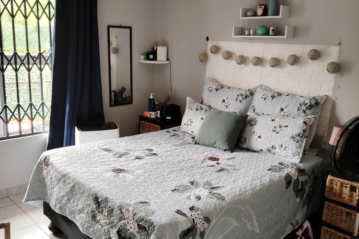 A functional bedroom featuring tiled flooring, a window with a security gate, and wall-mounted shelving units.