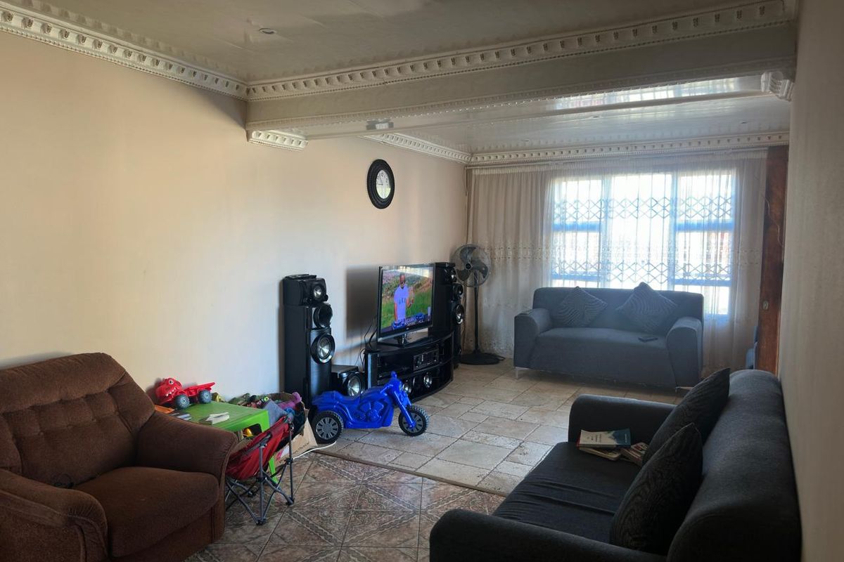 A spacious living room featuring decorative ceiling cornices and tiled flooring, offering a comfortable area for family relaxation and entertainment.