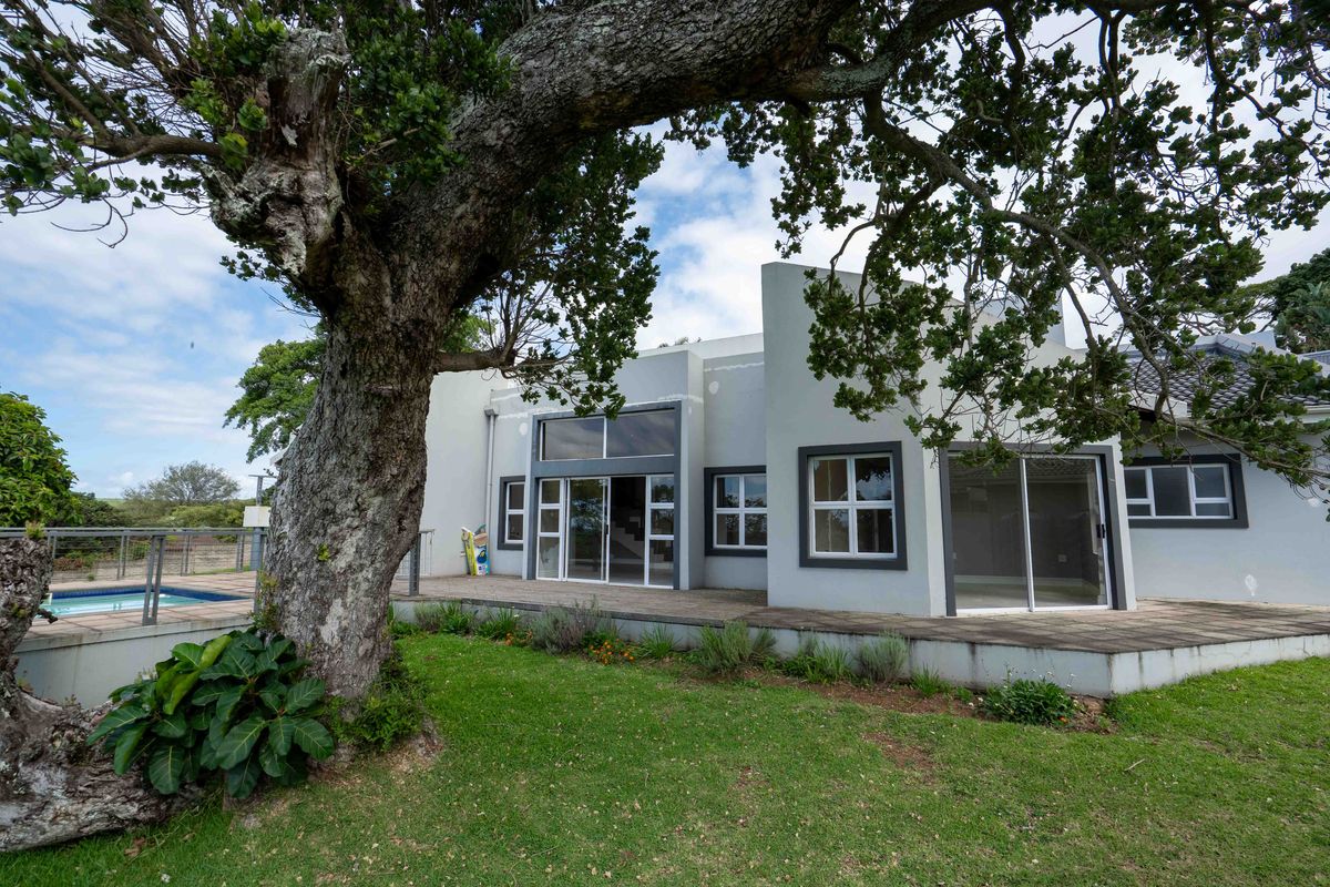 Rear exterior view of the townhouse featuring a paved patio, sliding glass doors, and an adjacent swimming pool under a large mature tree.