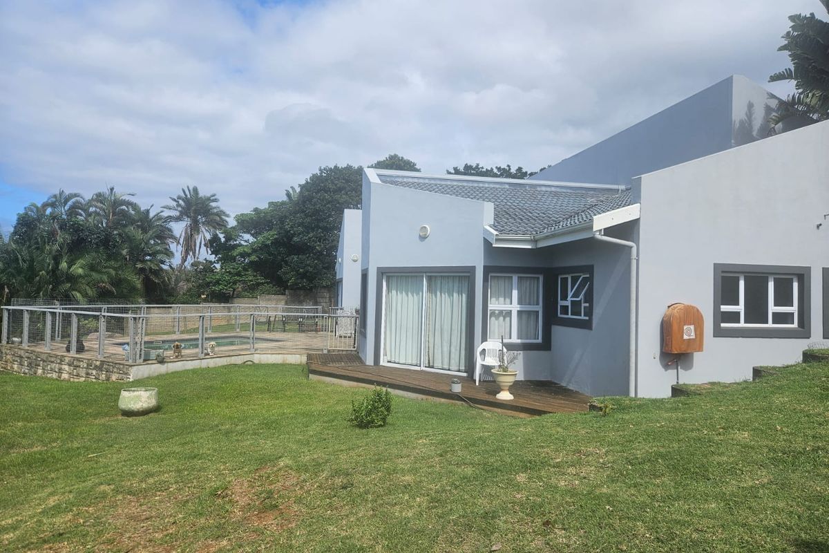 Rear view of the townhouse featuring a swimming pool with safety fencing, timber decking, and a well-maintained lawn area.