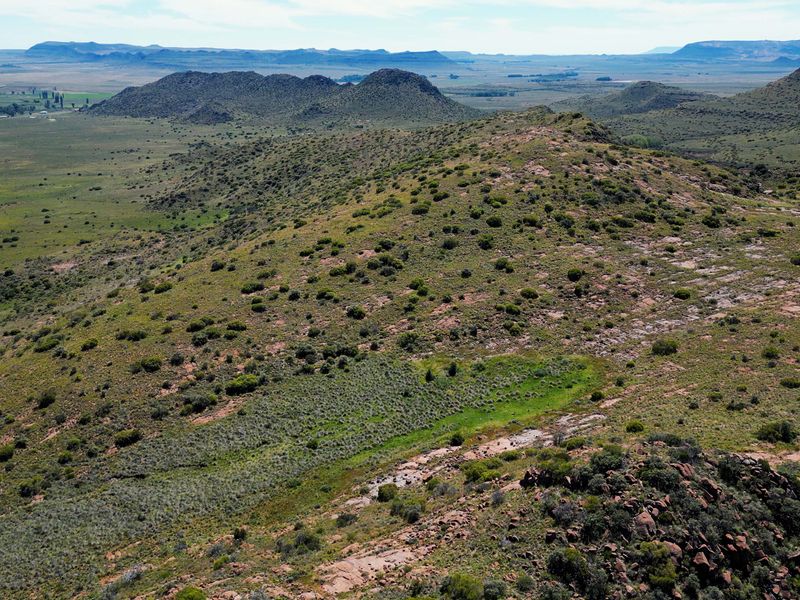 An expansive aerial view of the farm landscape, showcasing the natural topography, rolling hills, and vast open terrain characteristic of the property.