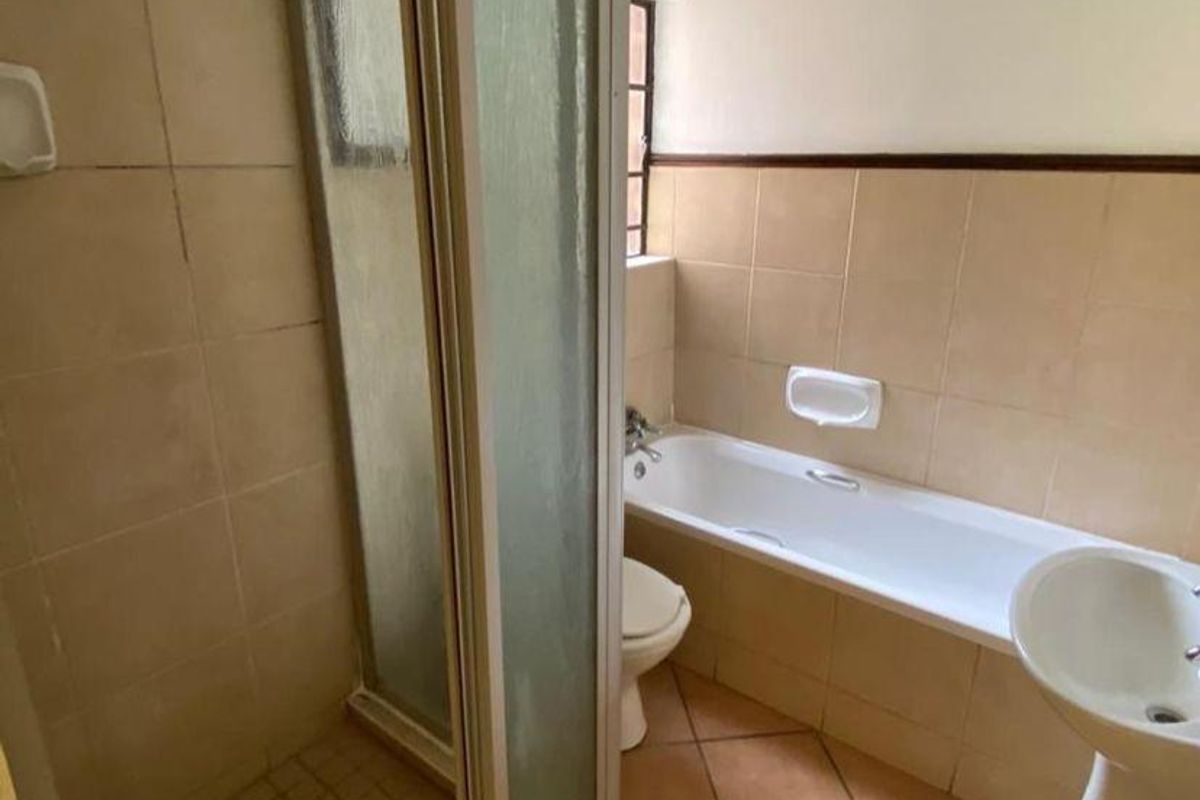 A functional bathroom featuring a shower enclosure, bathtub, pedestal basin, and toilet with neutral ceramic wall and floor tiling.