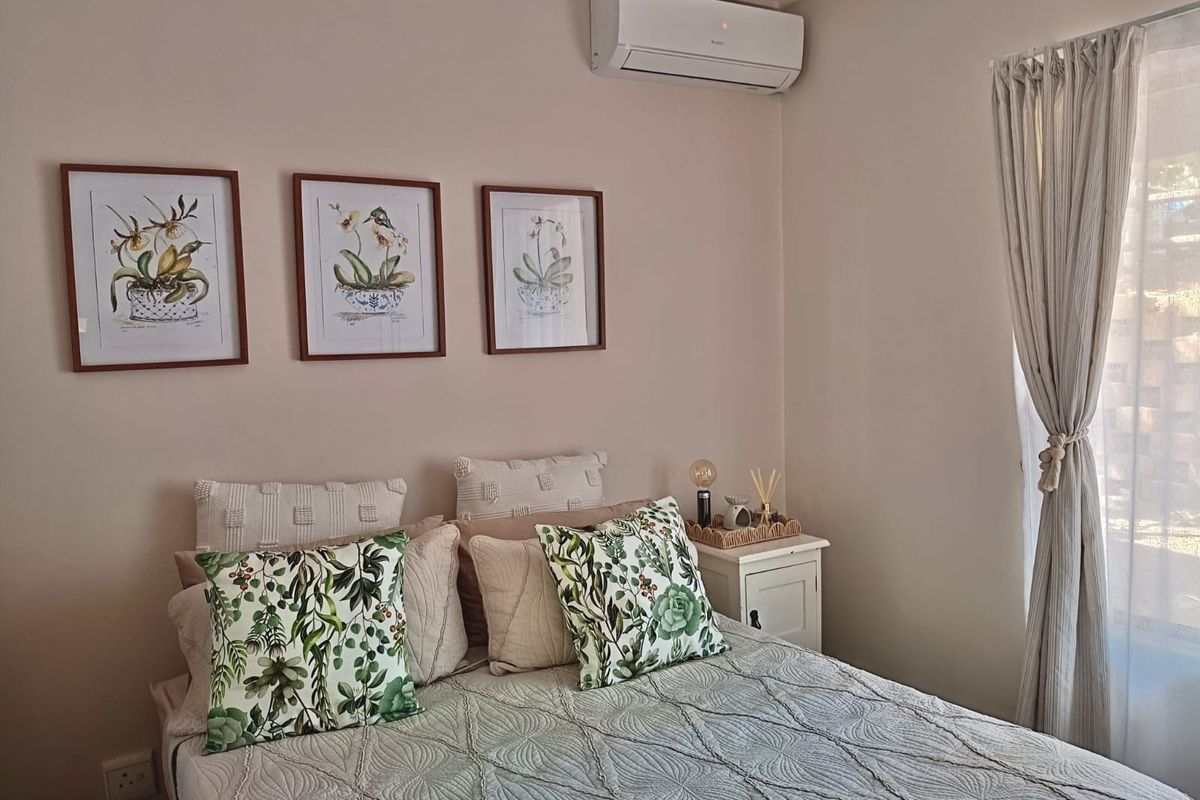 A well-maintained bedroom featuring a wall-mounted split-system air conditioner and neutral wall finishes.