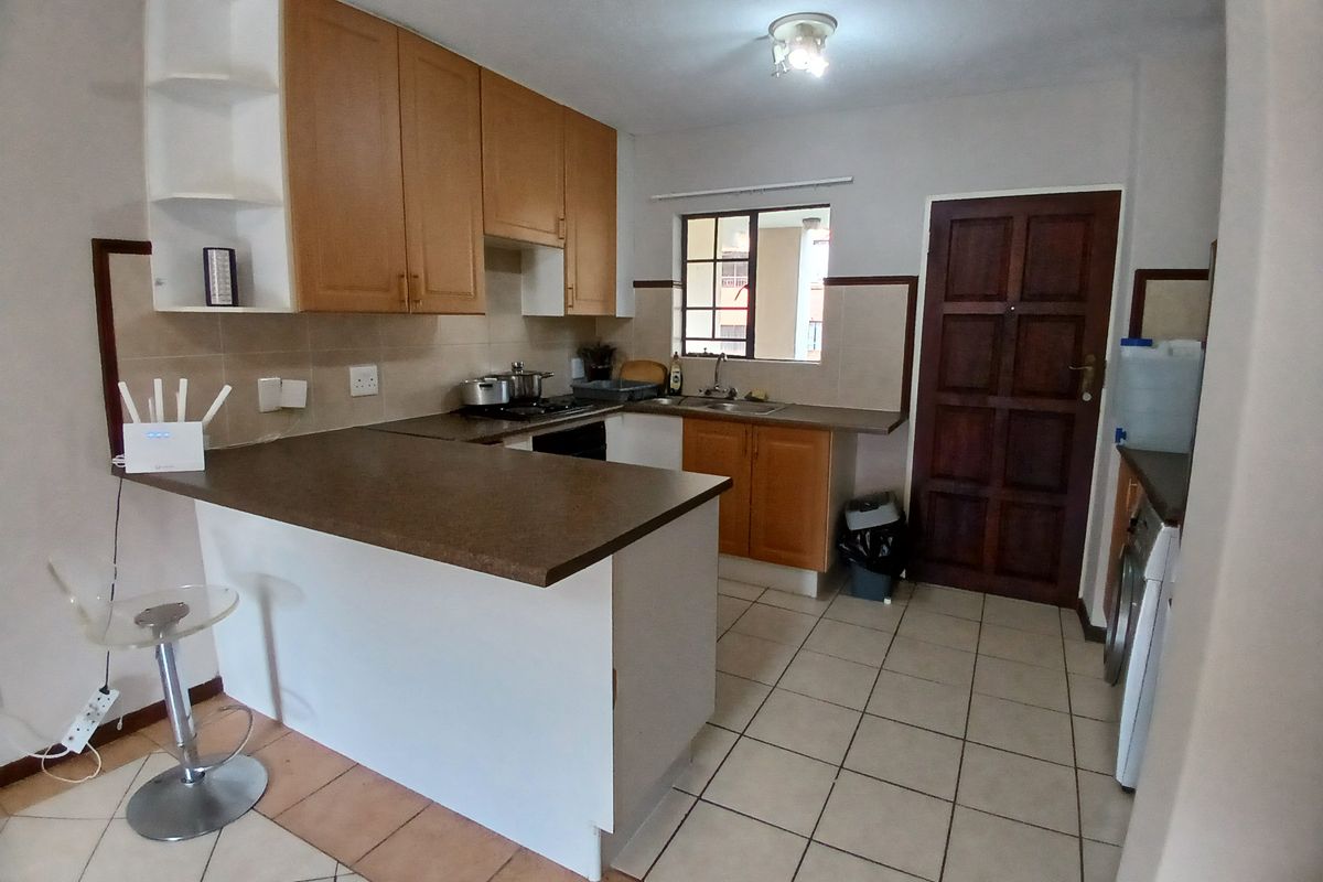 Functional kitchen featuring laminate cabinetry, tiled backsplash, double basin sink, and a breakfast counter, with ceramic floor tiles throughout.